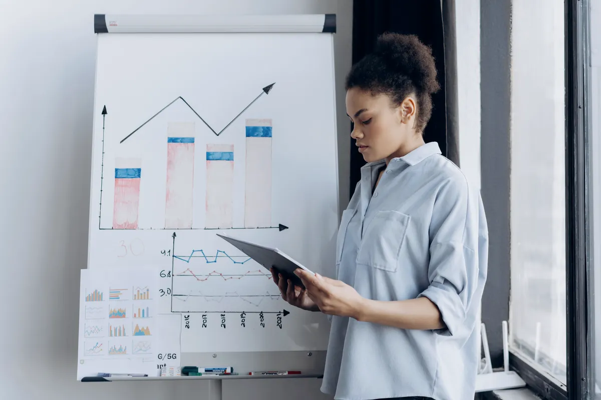 Une consultante présente une trajectoire de croissance devant un paperboard